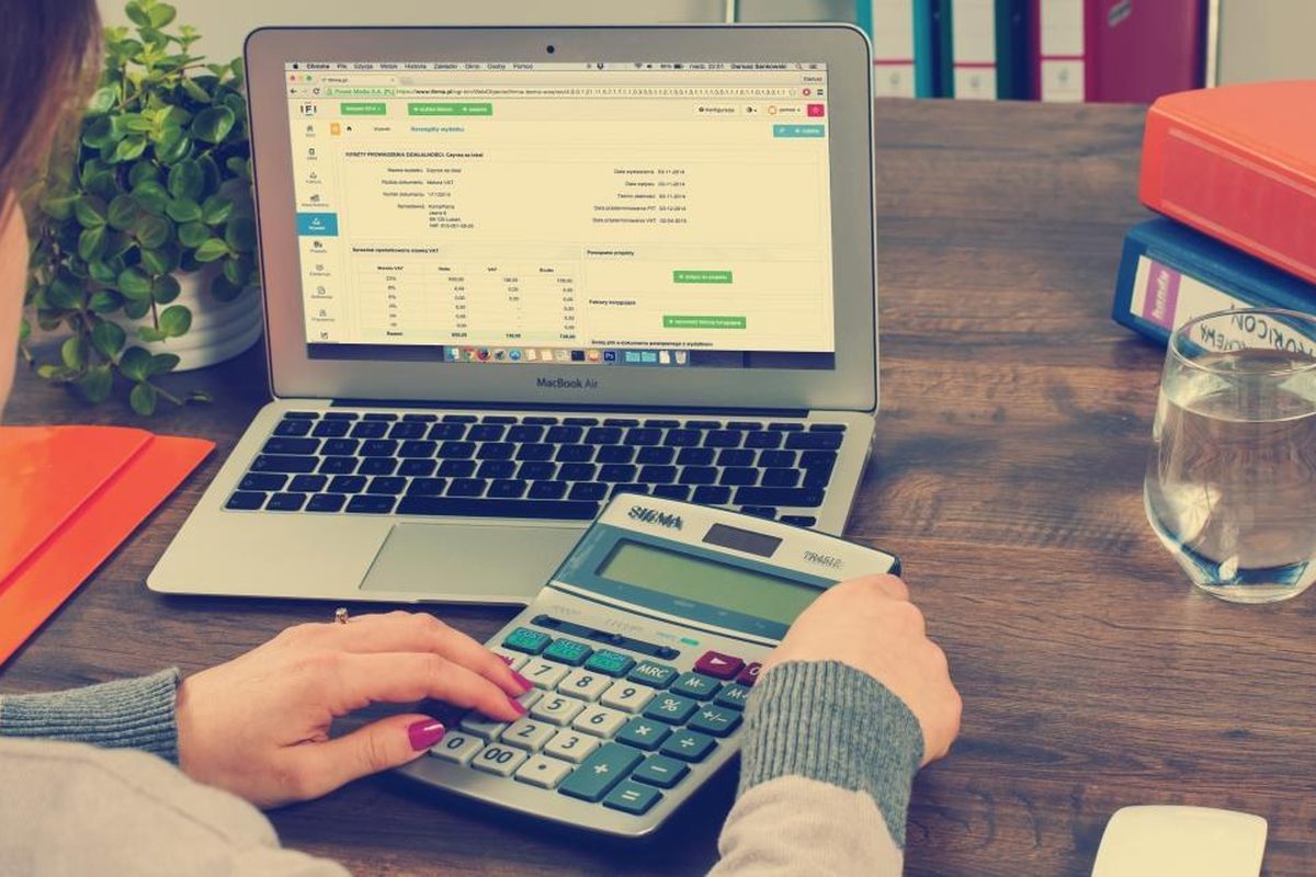 Accountant working through tax computations on a calculator and laptop