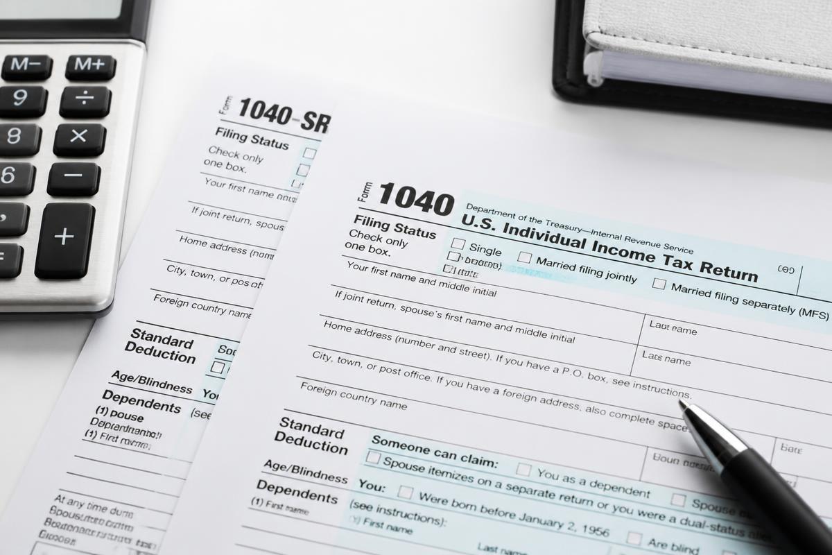 Tax return form, calculator and pen on a desk